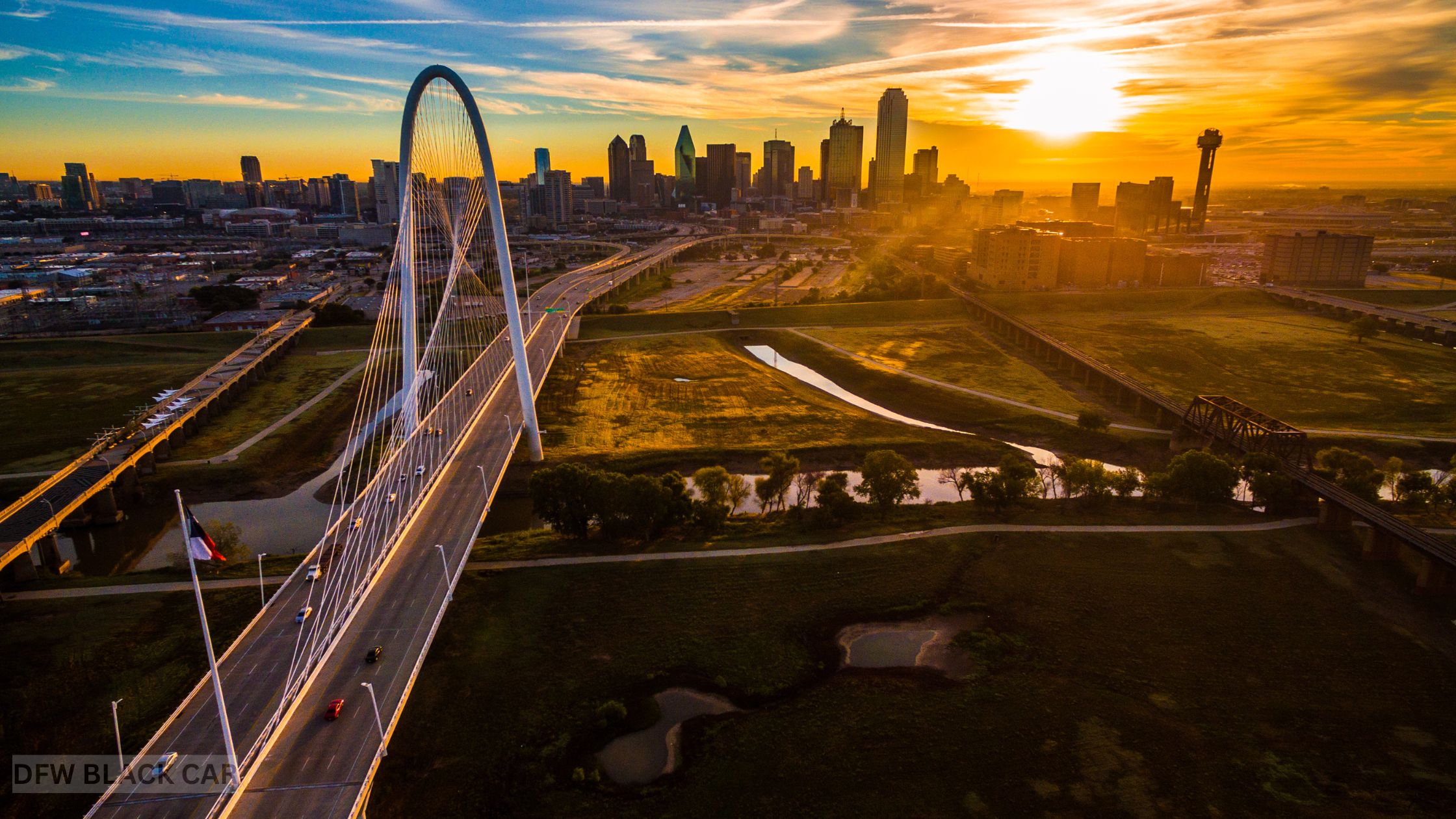 A breathtaking aerial photograph of Dallas, Texas, showcasing iconic landmarks like Reunion Tower, the Margaret Hunt Hill Bridge, and the downtown skyline at sunset.